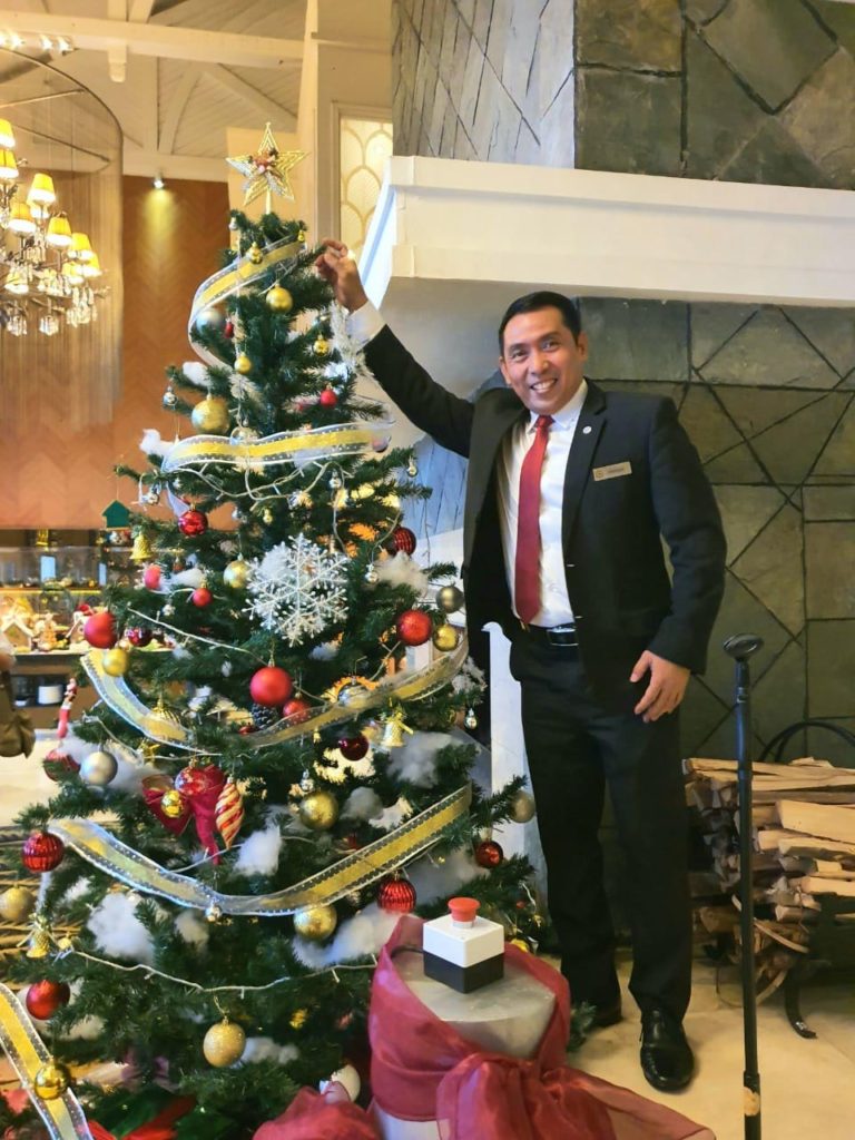 staff hotel sheraton bandung berdiri disamping pohon natal